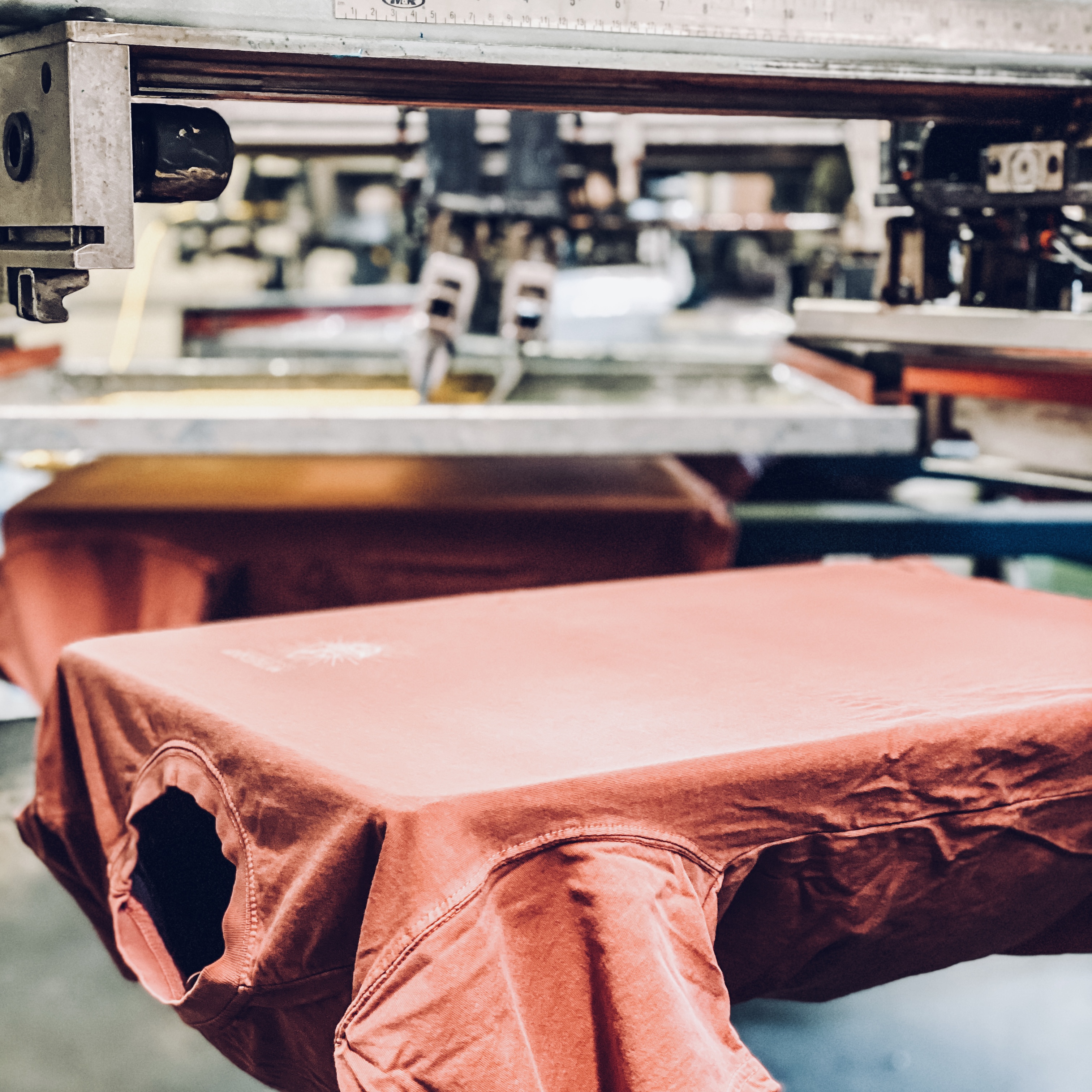 Red shirt being screen printed on a press